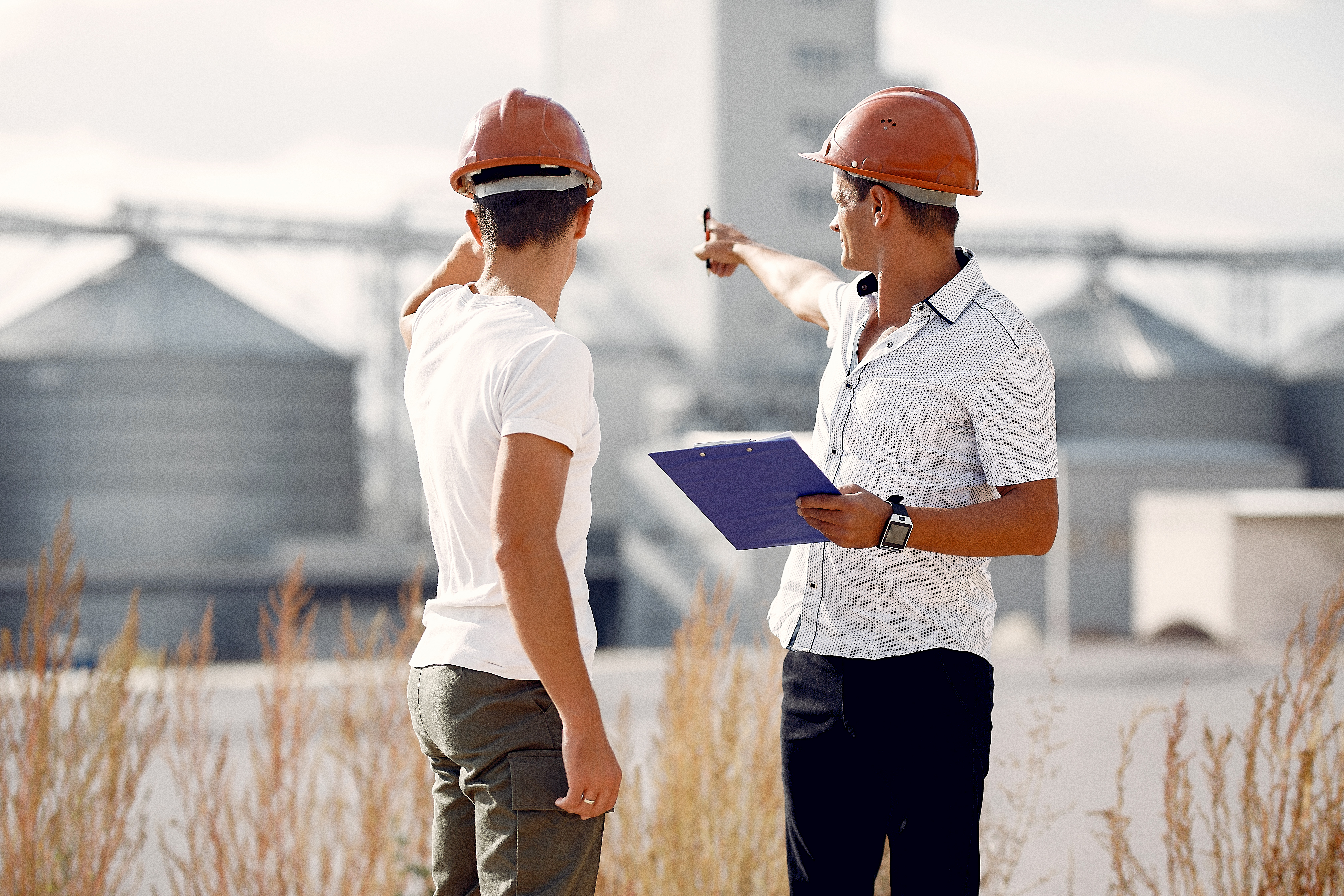 Engineers near the factory. Mtn in a helmet. Inspector looks at the building.